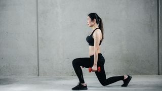 A woman performing a dumbbell reverse lunge