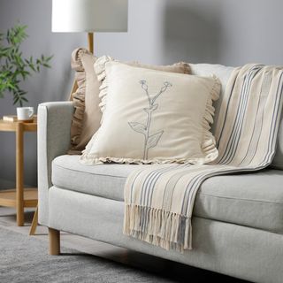 IKEA ÅKERNEJLIKA Cushion cover in white on a grey sofa in a living room