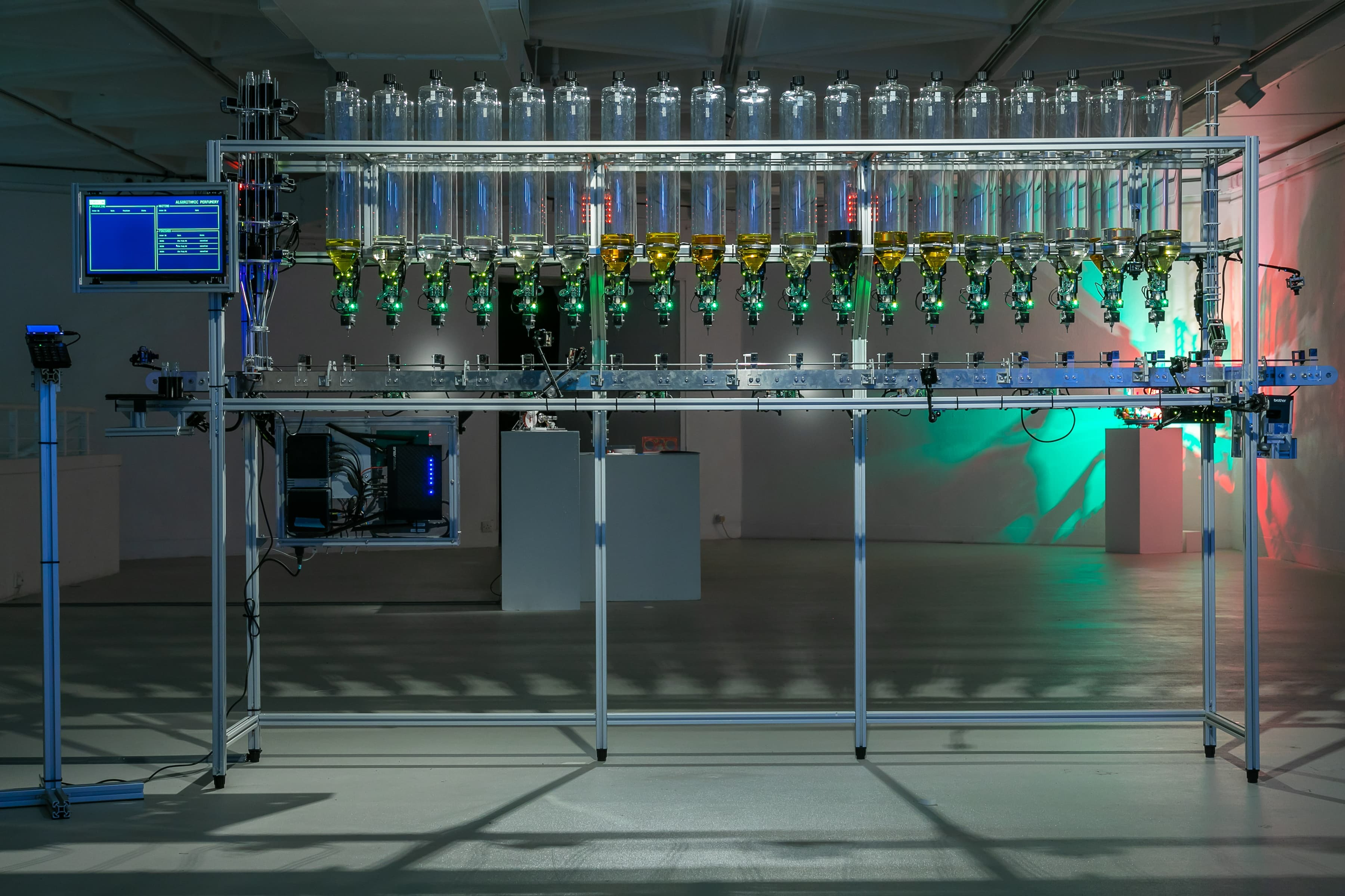 Perfume making installation, with computer screen and metal rack full of liquid dispensers