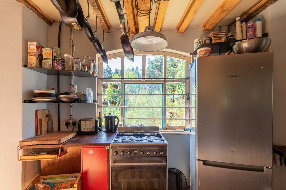 The kitchen has a visible wooden beam roof and pans hanging from the roof