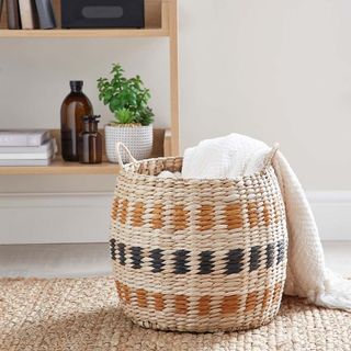 Dunelm Butterscotch Rush Basket with white blanket and bookshelf in the background