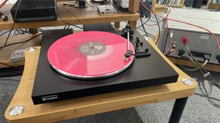 Rekkord Audio F110 turntable playing pink vinyl on wooden hi-fi rack