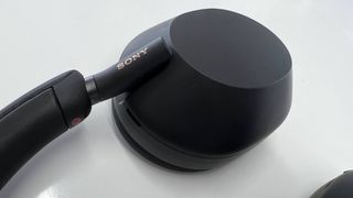 Nærbilde av Sony WH-1000XM5, liggende på et hvitt bord
