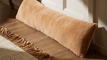 soft faux fur draught excluder resting on door