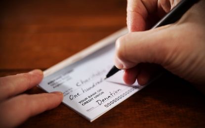 A person writes a check for a donation