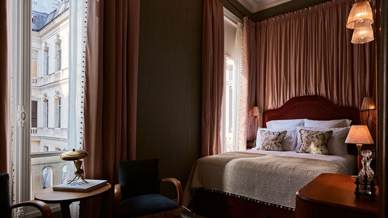 Paris hotels - a luxurious hotel bedroom with pink drapes and a grand bed