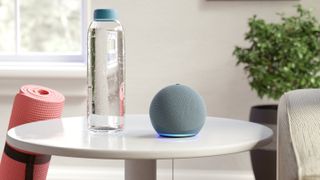 The Echo Dot sitting on a table next to a water bottle and a yoga mat.