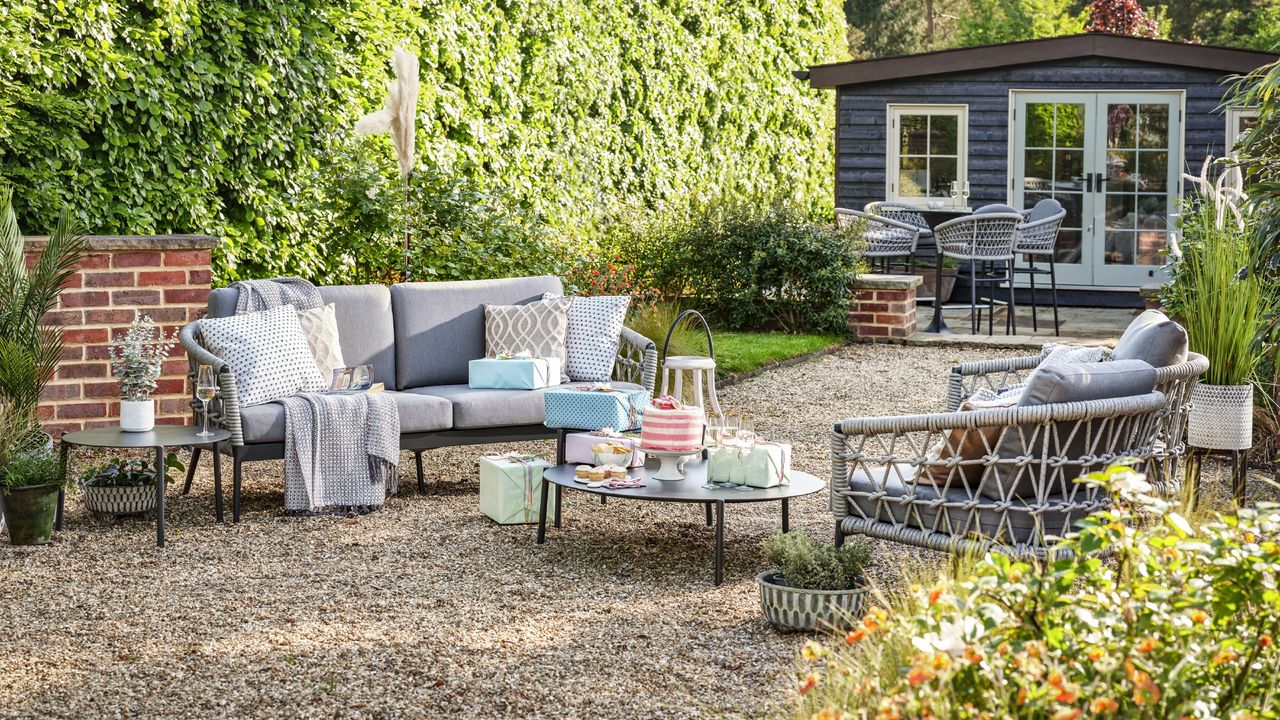 garden party ideas with sofa, chairs, coffee table with cake and presents, cushions and throws, shed and bar stool seating in background