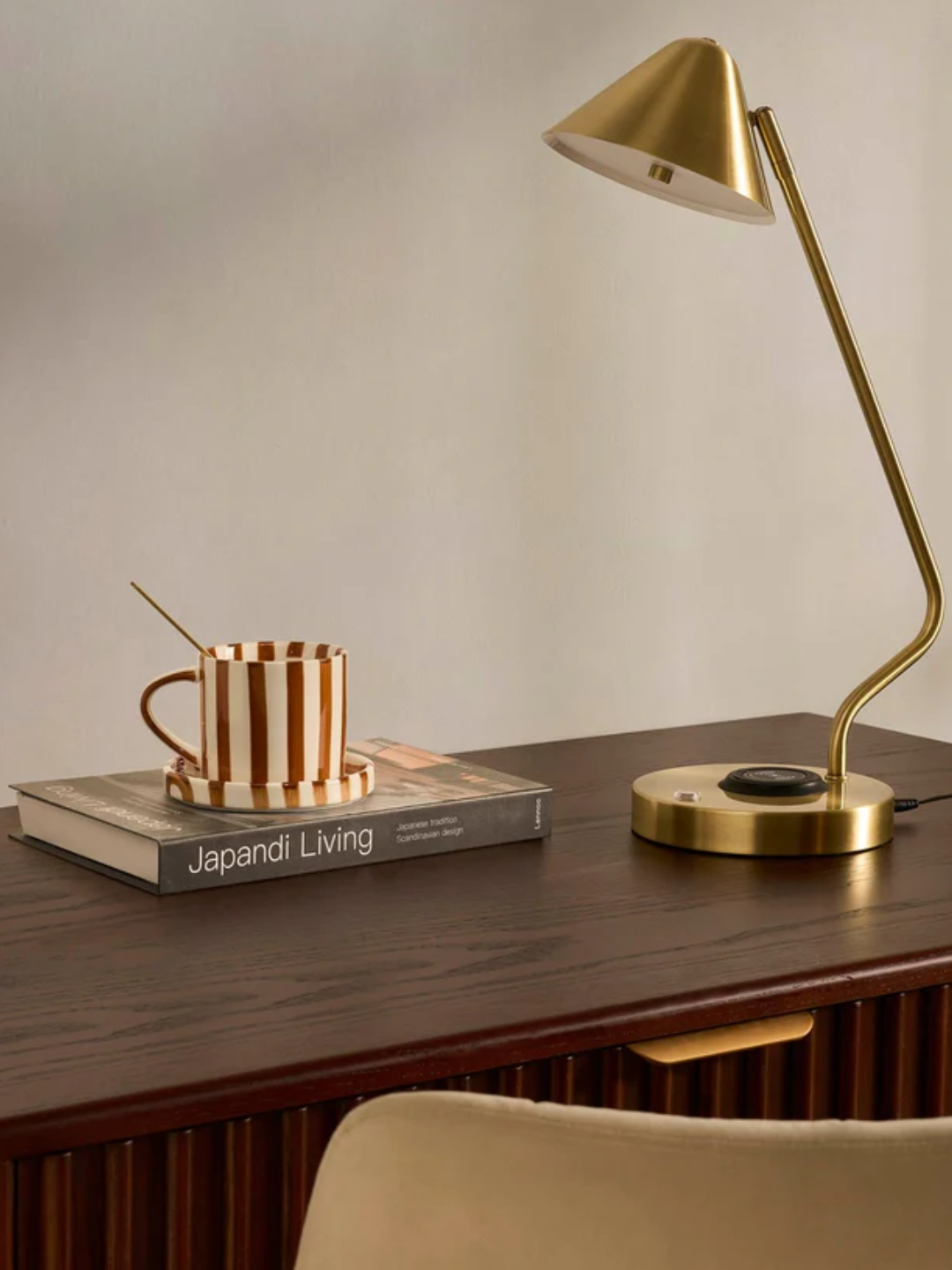 A brushed gold table lamp with a charging station from DUSK