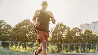 Man running on running track wearing sunglasses