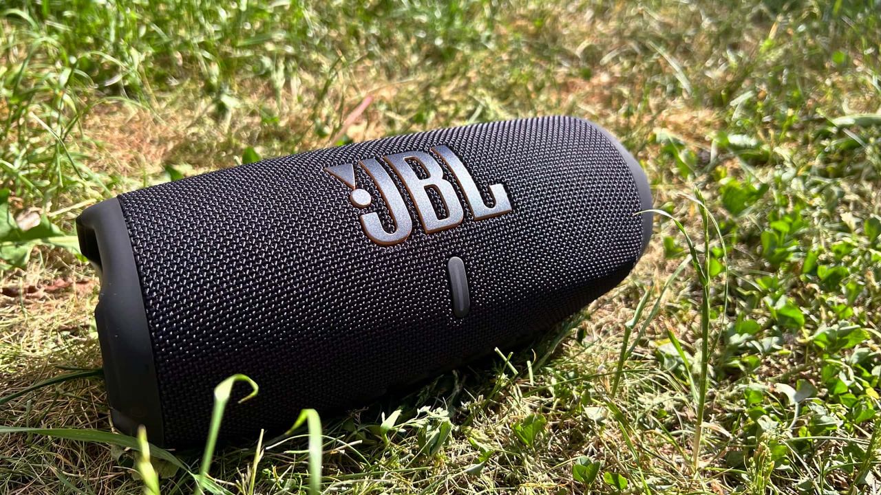 JBL Charge 5 Wifi med gr&auml;smatta i bakgrunden
