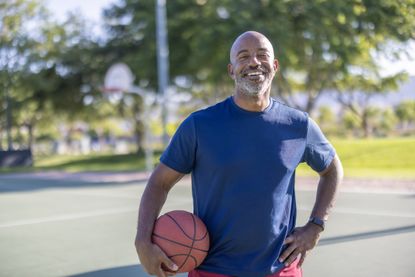 A portrait of an African American man at the park playing basketball.