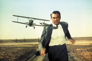 a man in a suit running a way from a low flying plane in North by Northwest