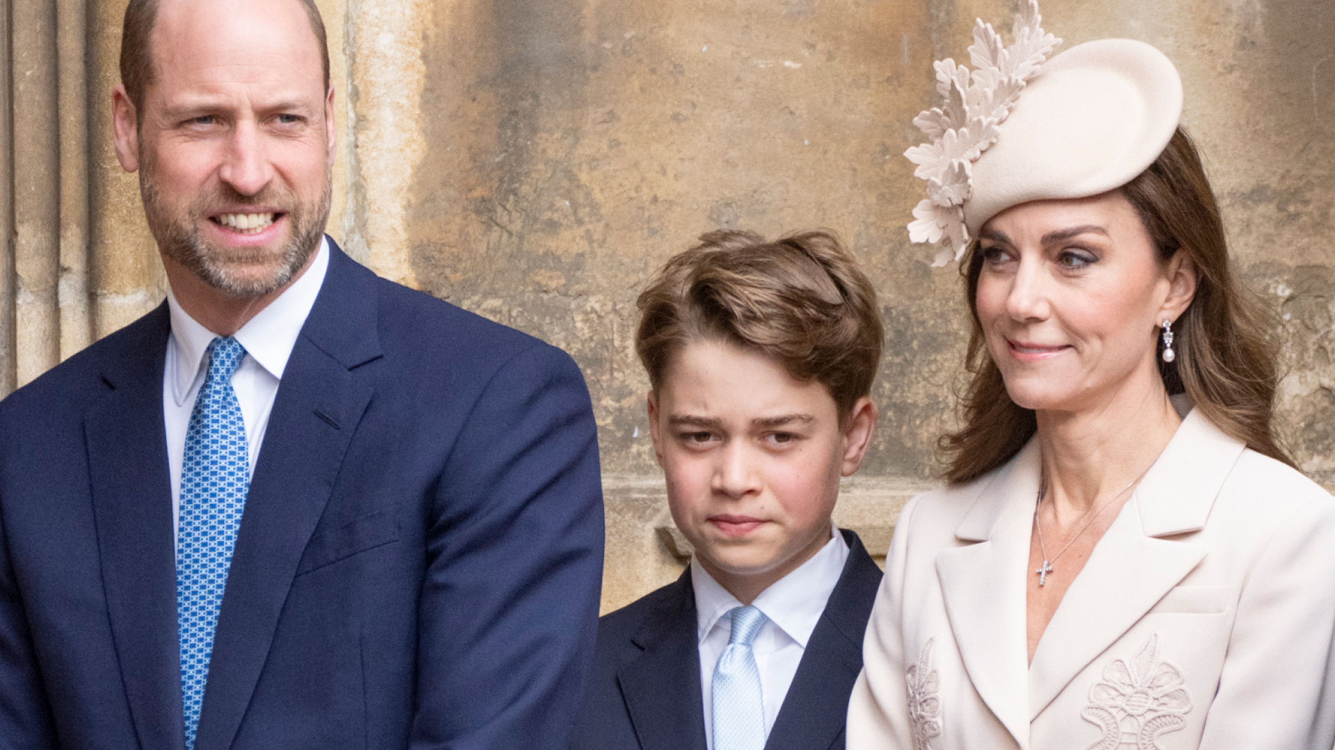 Prince George looks serious while wearing a navy suit and white shirt and has his hair combed to one side