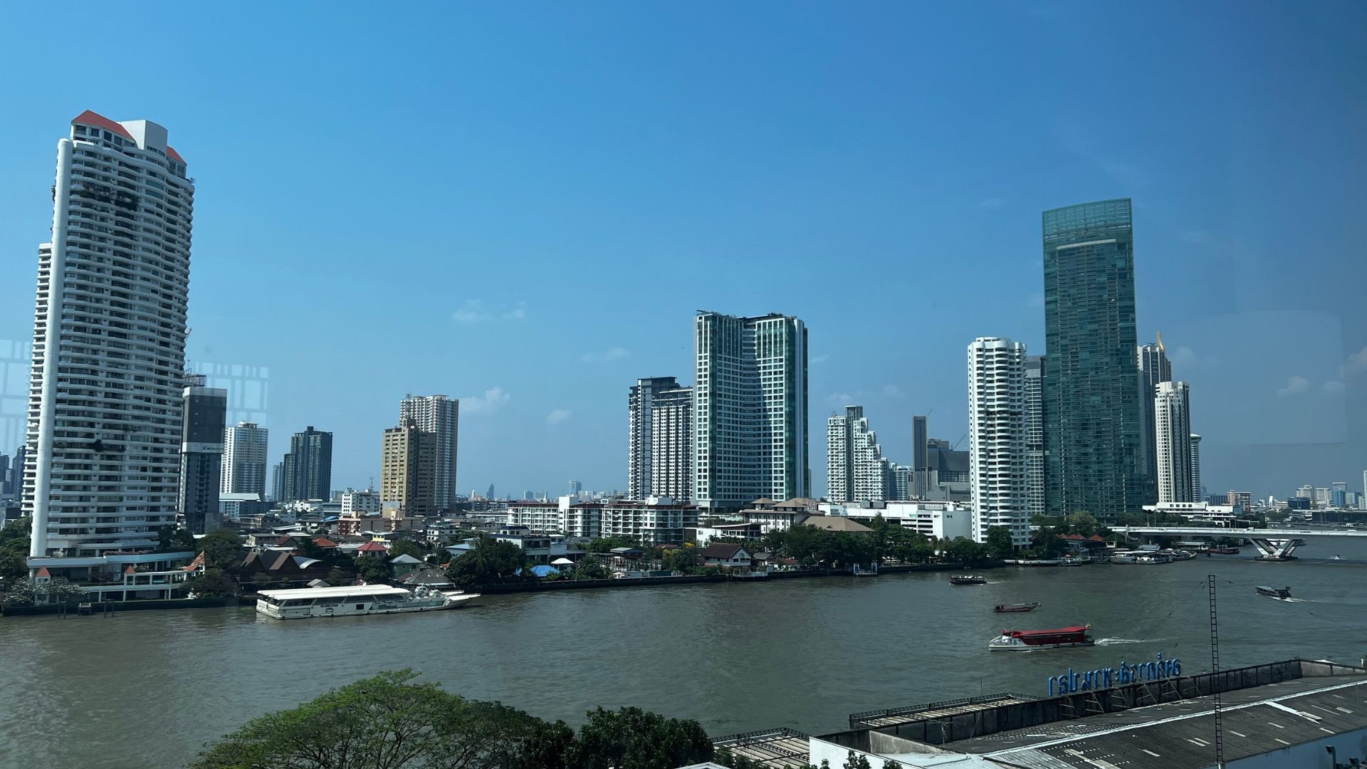The view from a riverfront room at Capella Bangkok, showing the river, boats and a city skyline