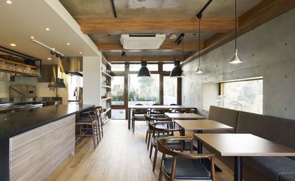 restaurant with wooden tables, benches and view into kitchen