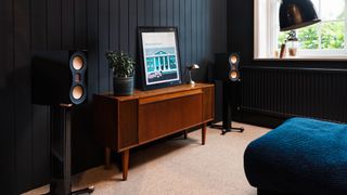 Monitor Audio Studio 89 bookshelf speakers on stands in moody lifestyle setting