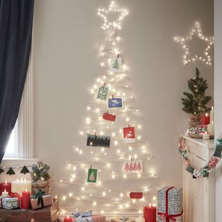 A wall Christmas tree made out of fairy lights with presents on the floor