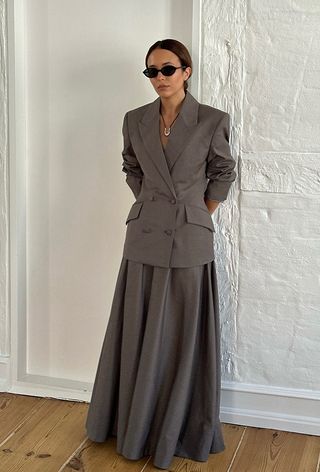 fitted blazer trend is shown on a woman wearing a tan tailored blazer with a matching maxi skirt