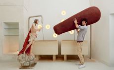 Man holding large red object in front of a statue