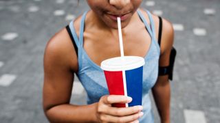 Runner drinking soda from a cup with a straw