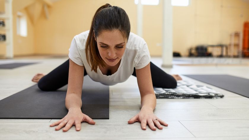 Woman performing frog pose during yoga class on yoga mat