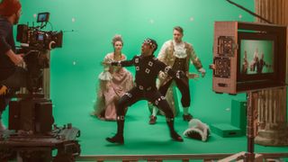 Directing green screen scene with gentleman protecting lady from actor playing monster wearing motion capture suit.