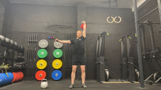 TechRadar fitness writer Harry Bullmore performing a kettlebell single-arm overhead press