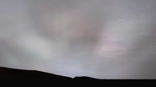 beams of light can be seen stretched across a cloudy sky over mars