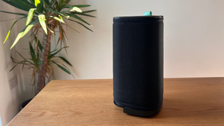 Air purifier on wooden table with plant to the left side in background