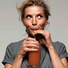 model in gray top sipping a drink from a straw