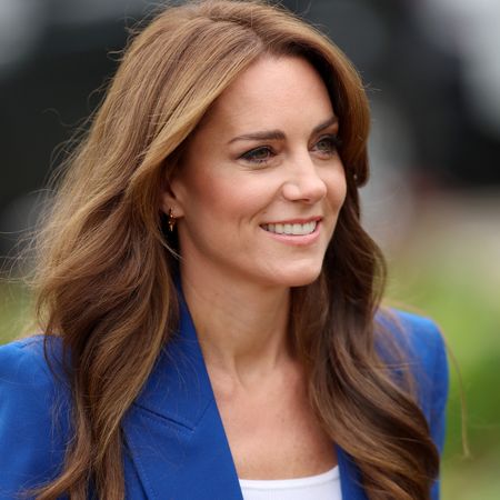 A headshot of Kate Middleton wearing a blue blazer with a white top under it smiling and looking to the right