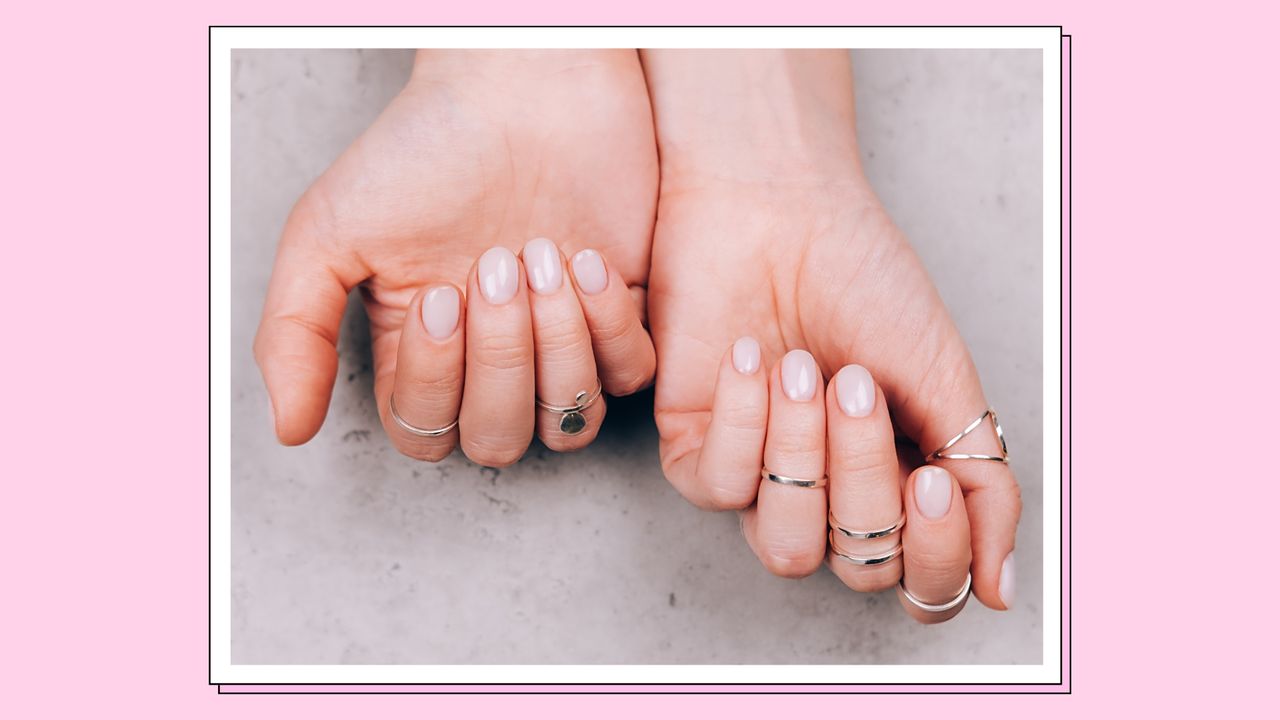 Lip gloss nails: Two hands with silver rings and a glossy, nude manicure/ in a pink template