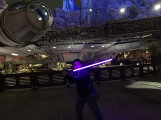 Wielding violet Power and Control lightsaber in front of Millennium Falcon