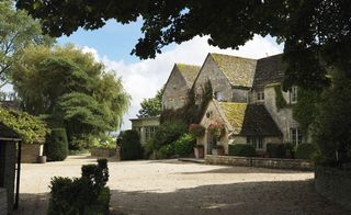 Exterior of Calcot Manor, Gloucestershire, UK with gravel driveway and topiary