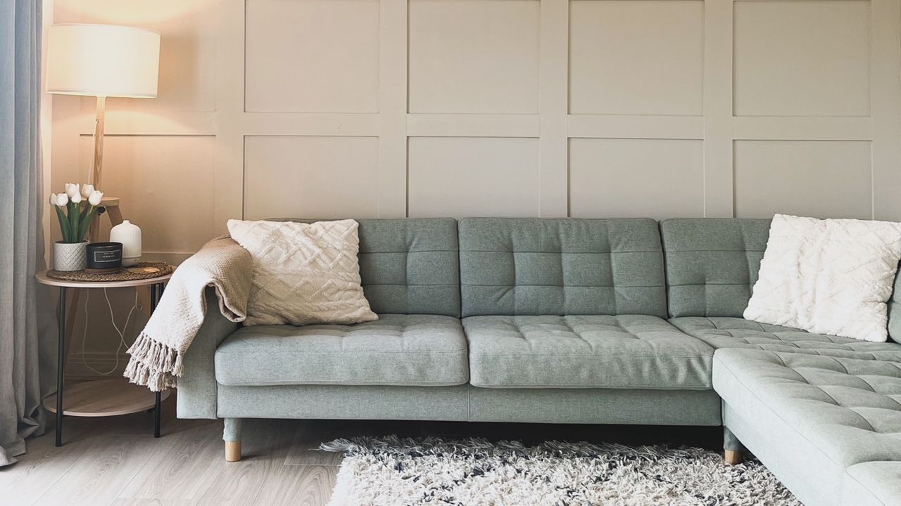 living room with wall panelling and green sofa