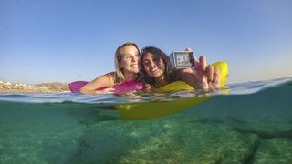 Two women taking a selfie with a GoPro Hero7 White in a lake