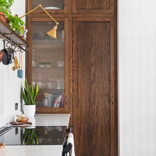 induction hob next to wooden kitchen storage unit underneath gold light