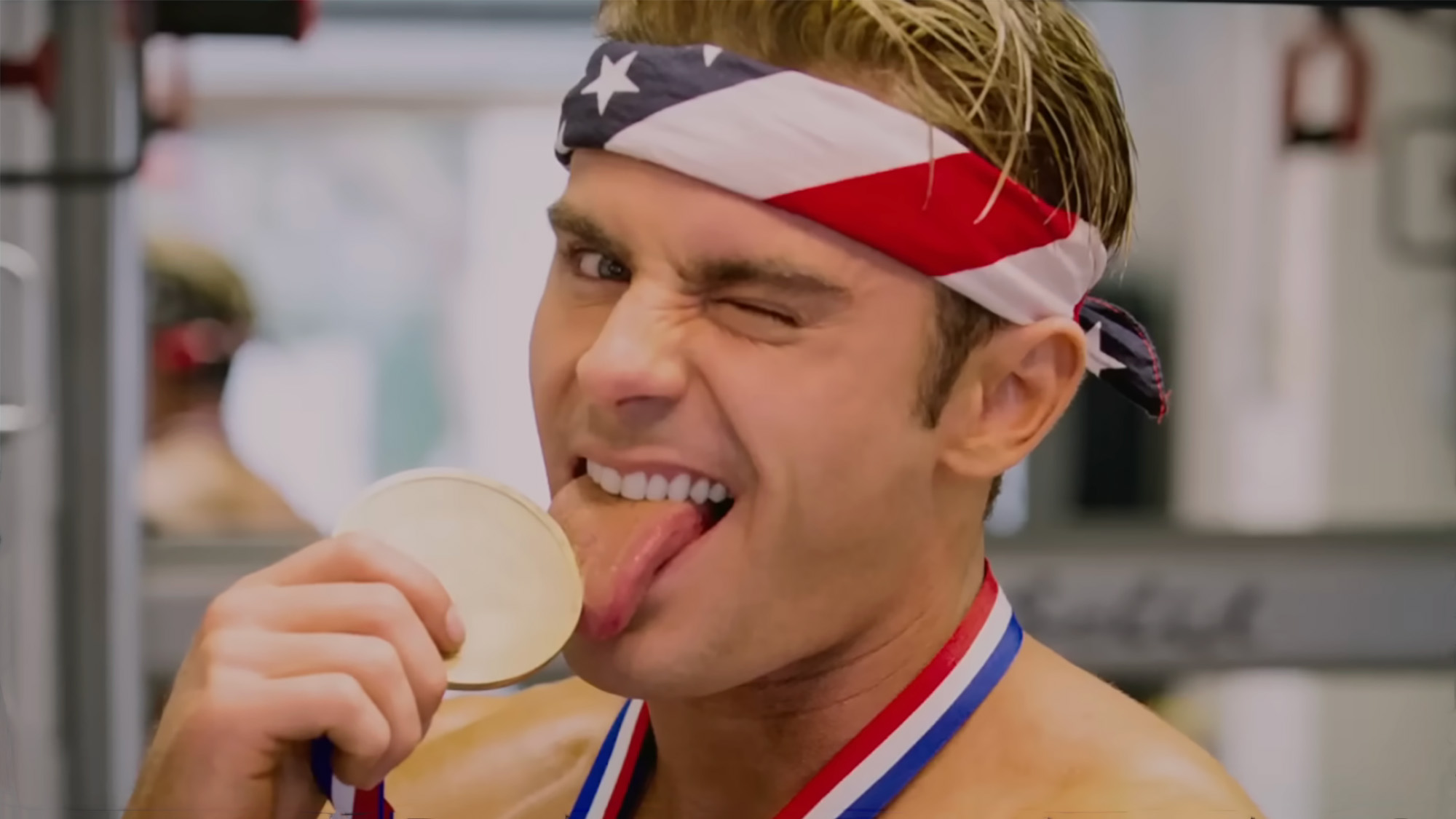 Zac Efron licking an Olympic medal in Baywatch 2017. 