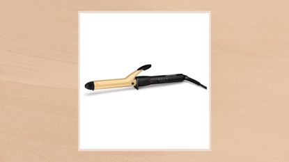 Image of the TRESemme Body &amp; Volume Classic Ceramic Curling Tong 25mm in a taupe frame set against an ochre watercolour-style background