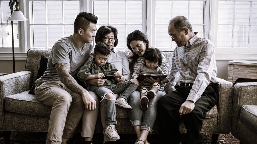 Three generations of a family sit together on a couch.