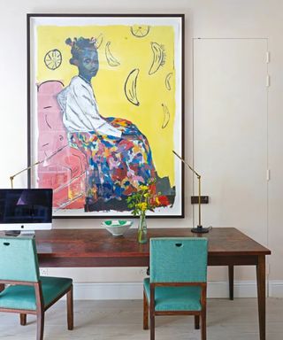 Home office with dark wooden desk, blue chairs and bold artwork