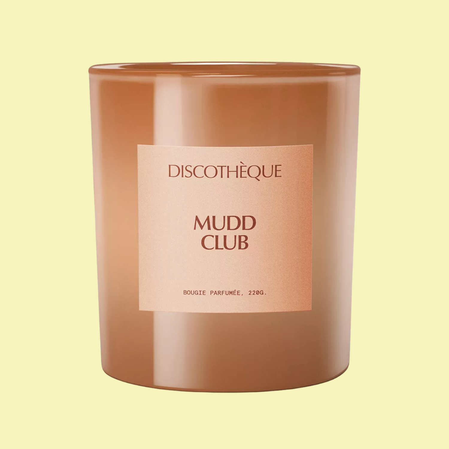 A brown candle against a butter yellow backdrop