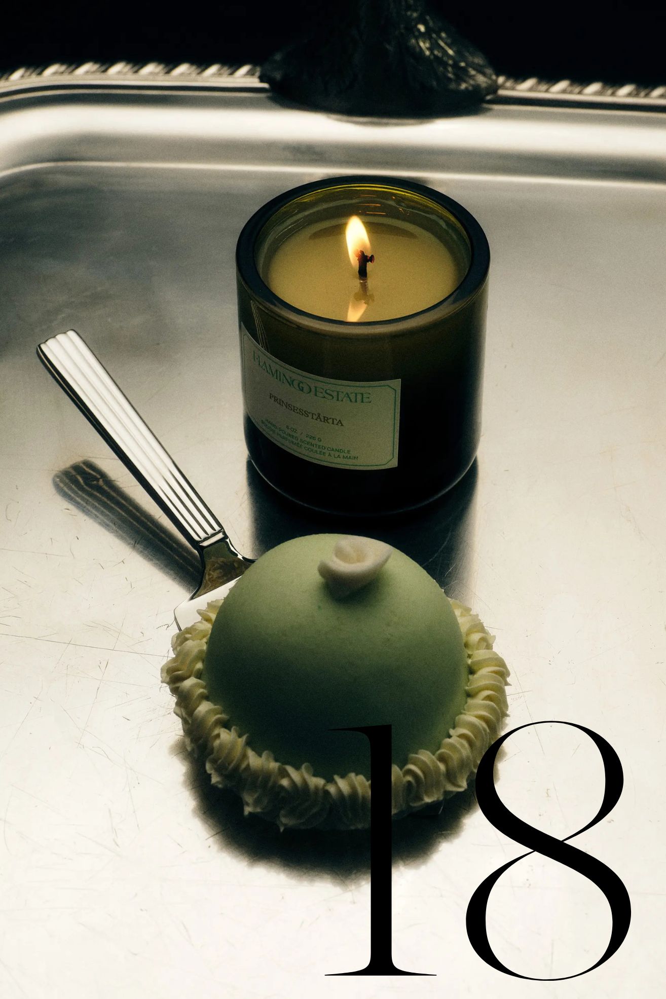 Flamingo Estate candle on silver tray next to green dessert