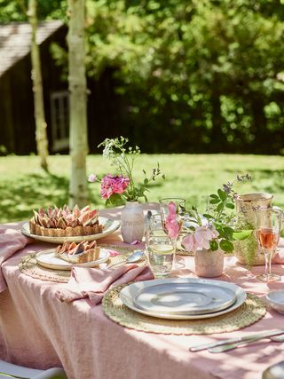 outdoor table laid with pink table cloth and grey plates