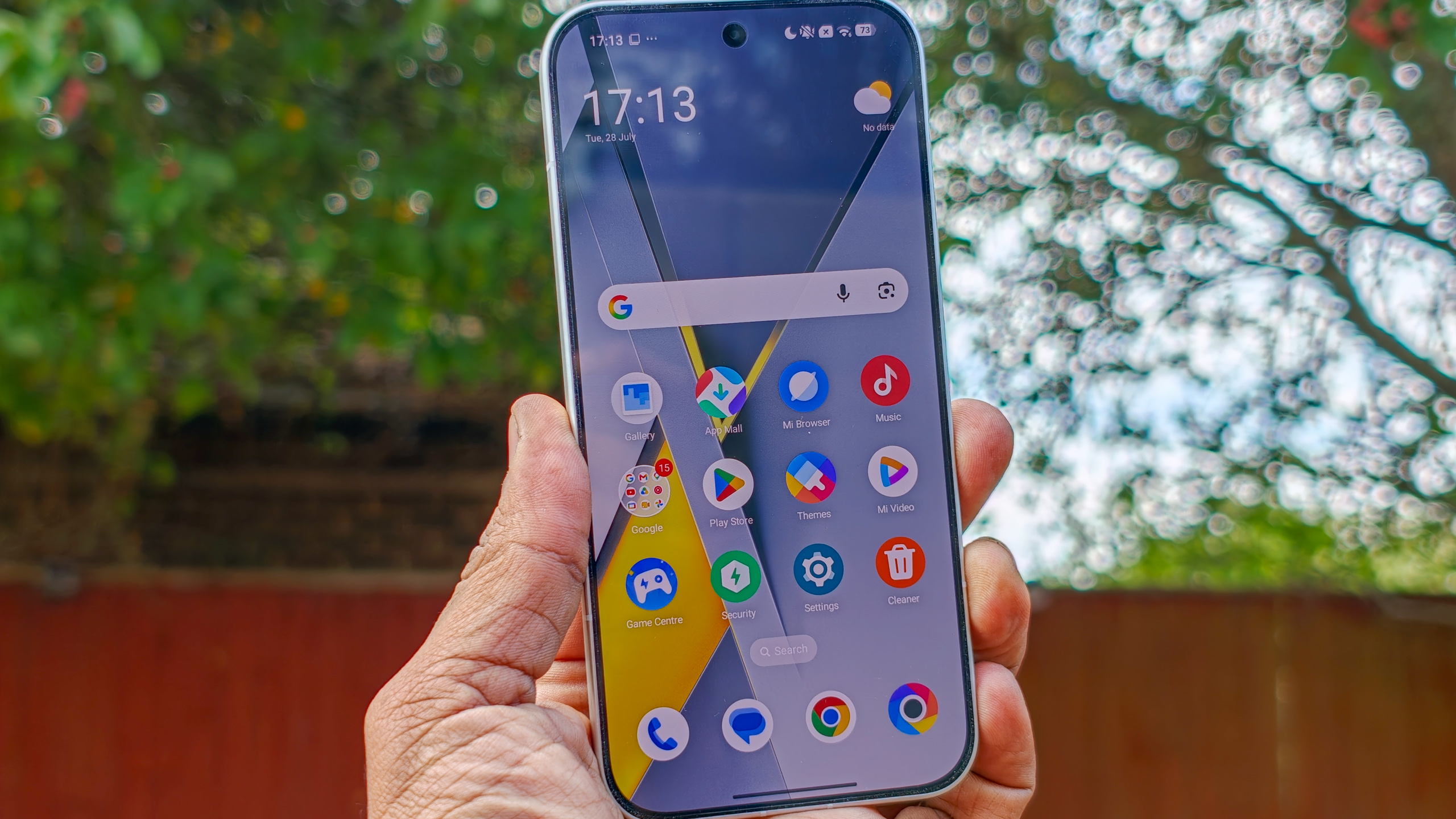 The Poco F8 Pro in Silver in the hand against a garden backdrop