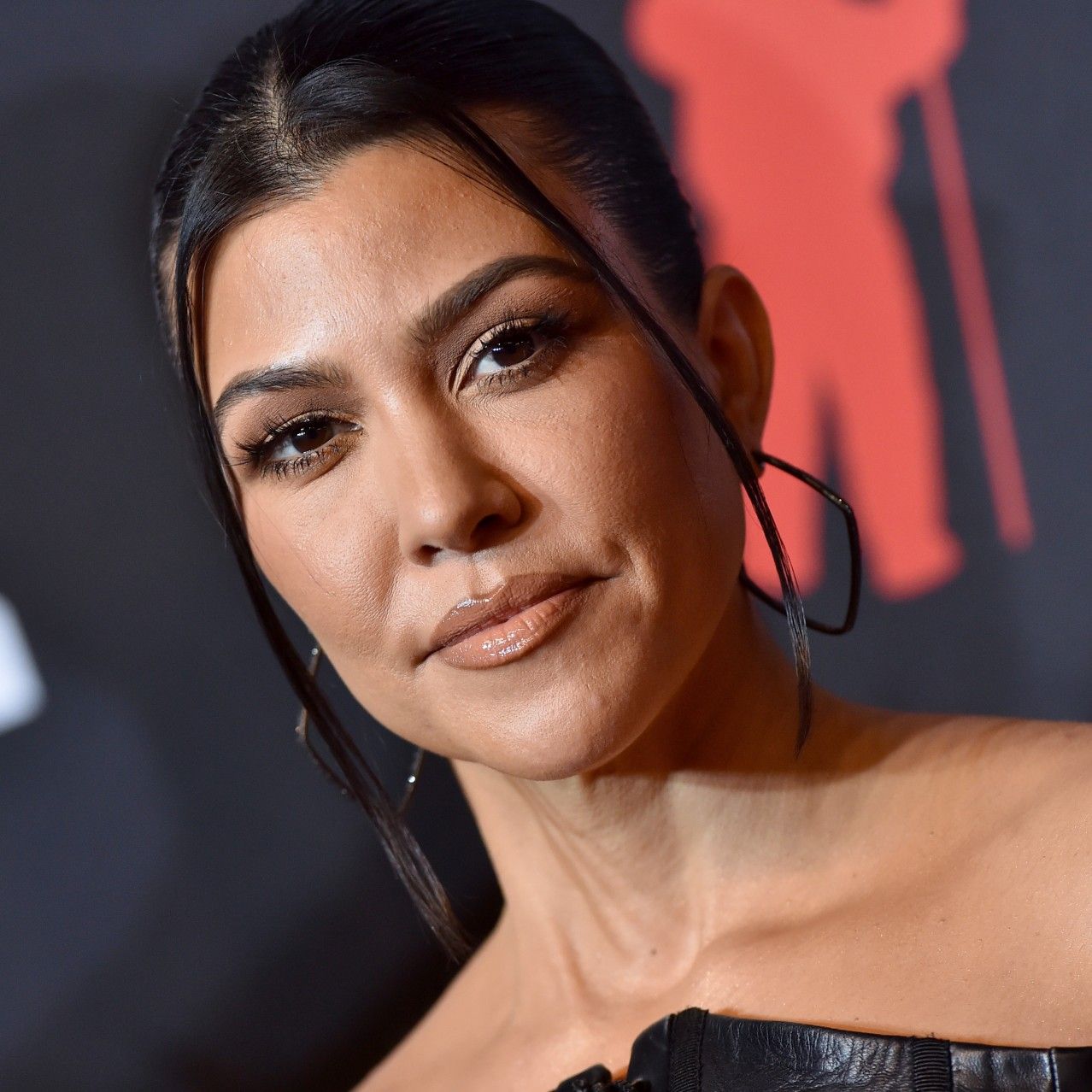 a close up photo of a woman with dark hair posing in front of a dark background on a red carpet