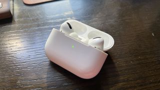 An AirPods Pro case open with AirPods Pro inside and green light on