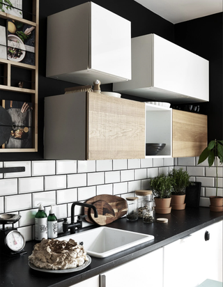 a black and white kitchen with white subway tiles, black countertops and storage cubes mounted on the wall with a range of shelving