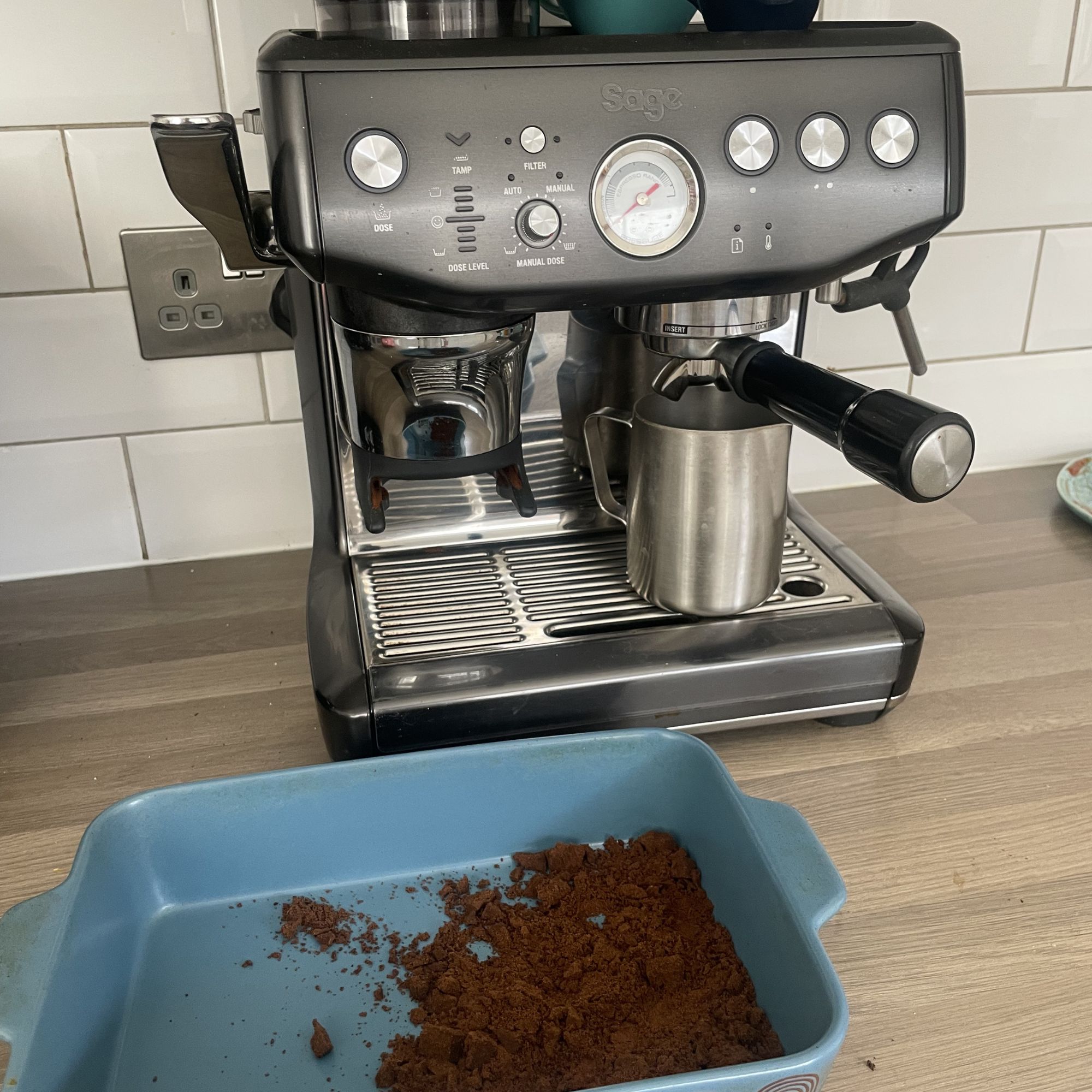 Grey Sage coffee machine sitting on a kitchen worktop, with a blue dish of coffee grounds sitting in front of it